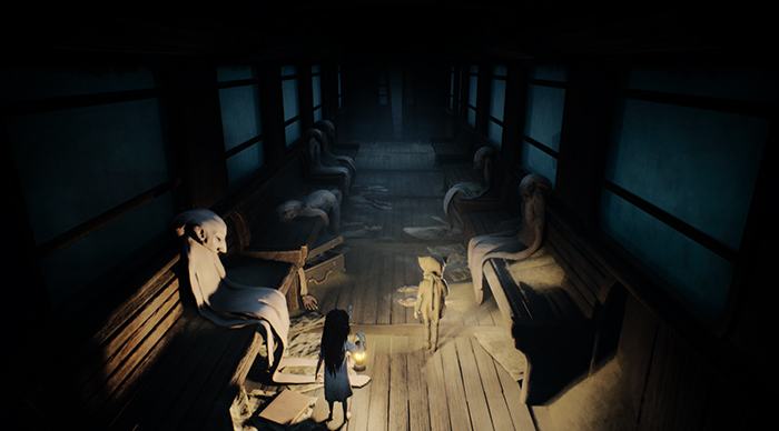 Inside a train car, the characters walk past rows of empty seats draped in ghostly cloaks.