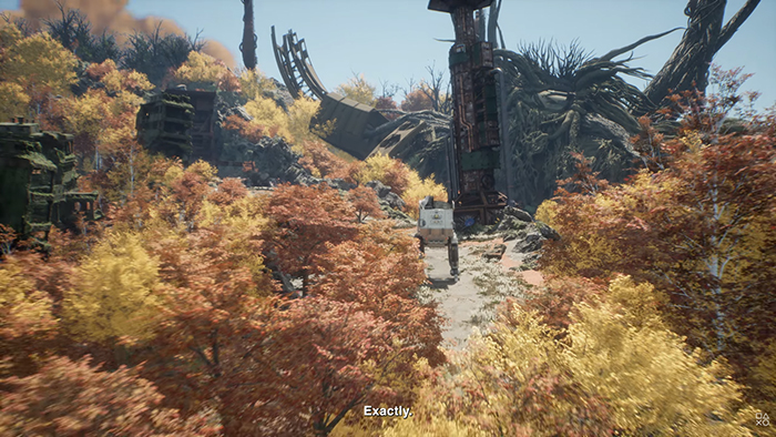 Emma walks down a quiet path through a vibrant autumn forest, surrounded by golden and red trees. Ruined structures loom in the distance, hinting at a world shaped by past conflict and nature’s reclaiming power.
