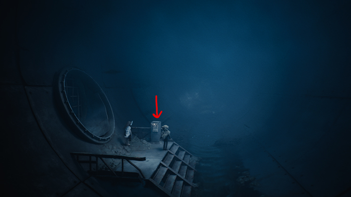 The duo activates a control panel near a massive pipe arrow shows interaction point.