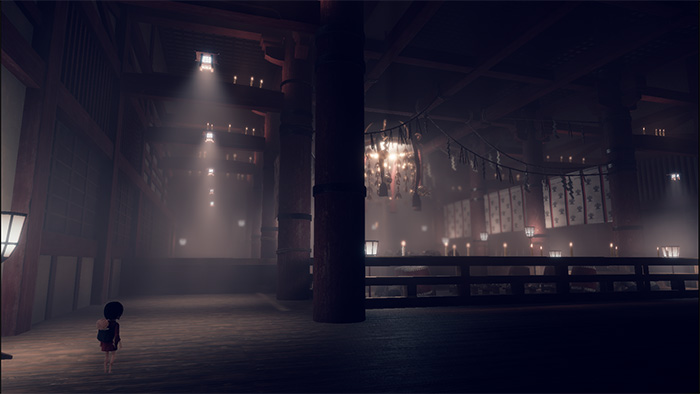 A small girl character stands alone in a massive, dark traditional Japanese hall. The space is filled with pillars, hanging lanterns, and distant lights, creating a sense of scale and mystery. Dust particles float in the air, adding to the eerie, abandoned atmosphere.