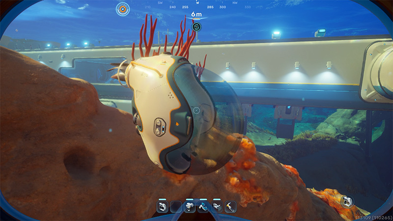 The Tadpole vehicle hovers sideways against a rocky outcrop; behind it, vibrant red soft coral polyps extend upward from the reef.