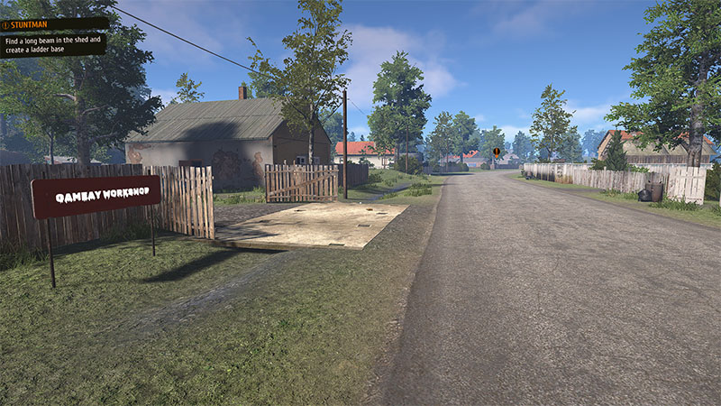 Dirt road with "GAMEAY WORKSHOP" sign; shed and wooden fence in background; quest prompt: "STUNTMAN: Find long beam in shed and create ladder base".