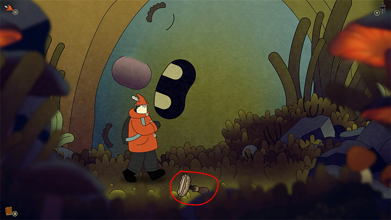 A character stands in a cave with a giant sleeping face (resembling a colossal figure) in the background; a ceramic cup on the ground, highlighted by a red circle, is an interactive object.