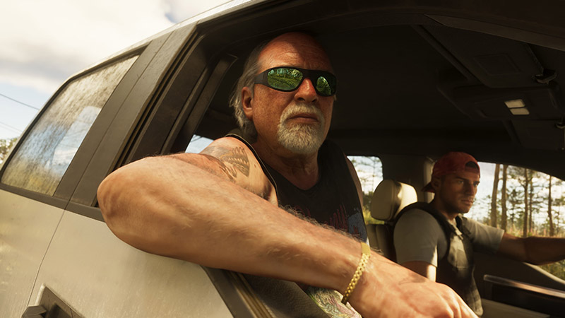 GTA6 character Brian Heder leaning out of a vehicle window: an older white man with a gray goatee, balding head, green-tinted sunglasses, and visible arm tattoos (including a tribal-style design). He wears a black sleeveless tank top and a gold chain bracelet. 