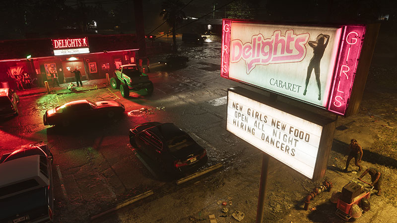 GTA6 official scene: Nighttime aerial view of “Delights Cabaret”—a neon-lit strip club with pink signage featuring a silhouetted dancer; marquee reads “NEW GIRLS NEW FOOD / OPEN ALL NIGHT / HIRING DANCERS”; parked cars (including a green truck and black sedan), wet pavement reflecting lights, and two figures near a dumpster in the foreground.