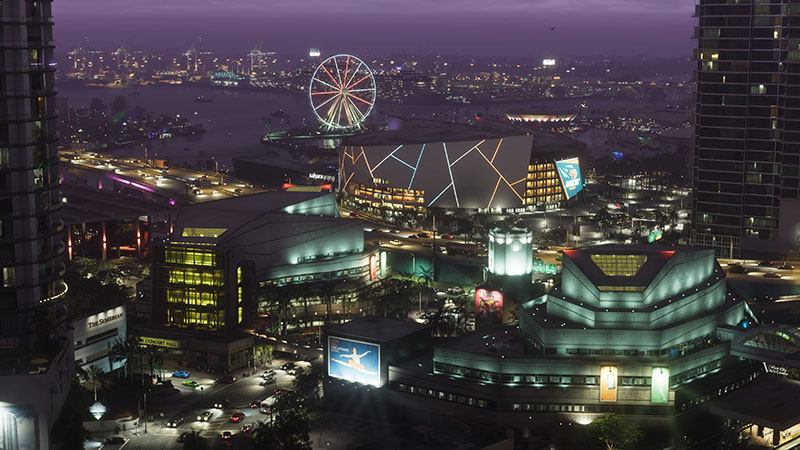 GTA6 official scene: Twilight aerial view of a neon-lit entertainment complex—featuring a glowing Ferris wheel, geometrically faceted arena with dynamic lighting, tiered theaters, and bustling streets; distant harbor and city skyline shimmer under purple-hued dusk.