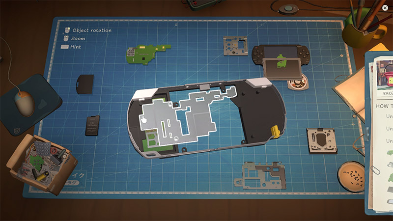 A disassembled handheld gaming device lies on a blue grid cutting mat, surrounded by removed parts, tools, and a mouse.